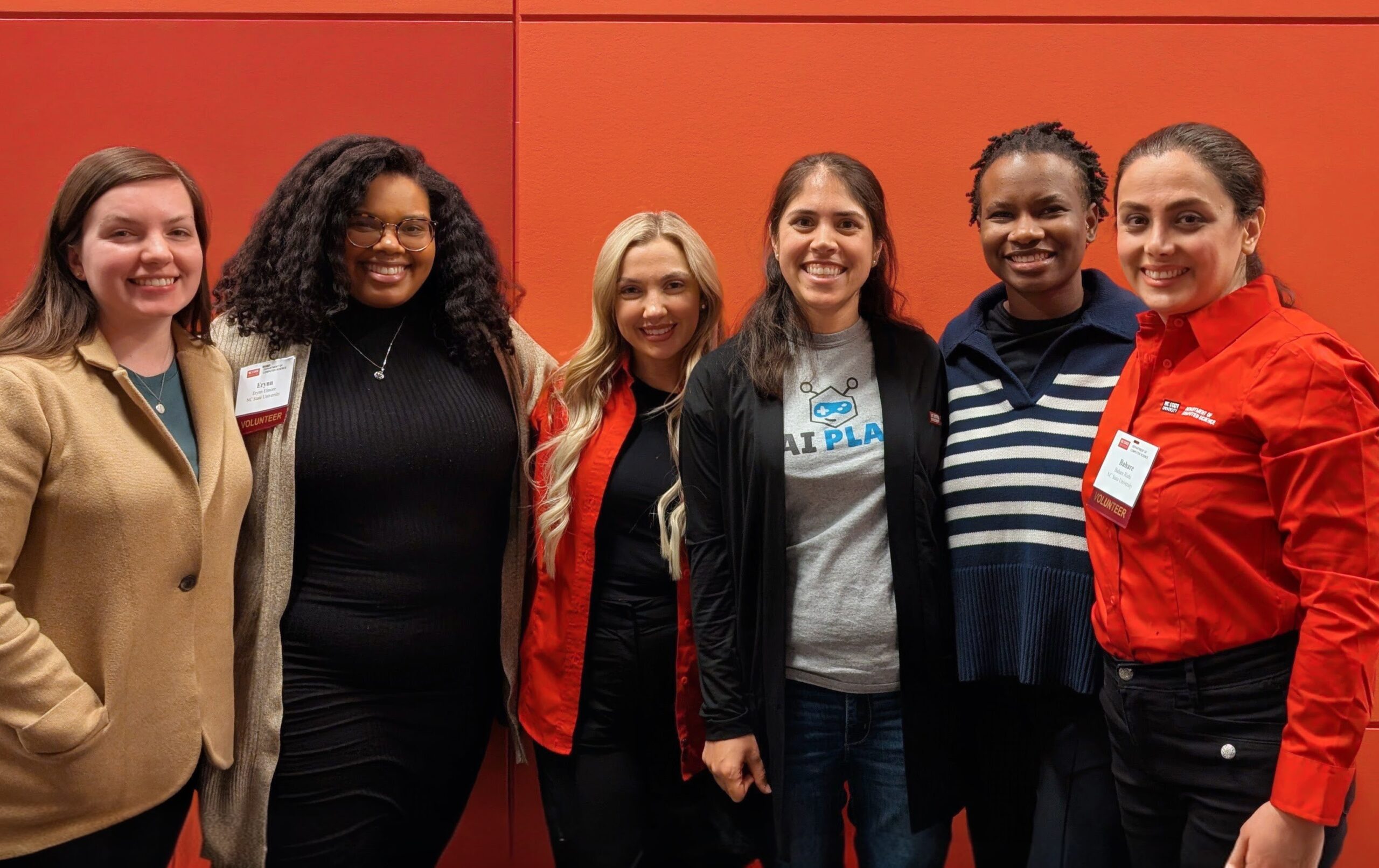 A group of people posing for a photo on a red background