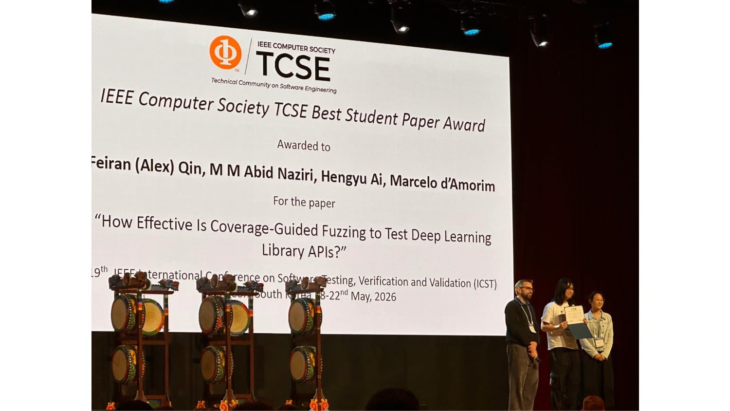 People accepting an award up on a stage in front of a large screen