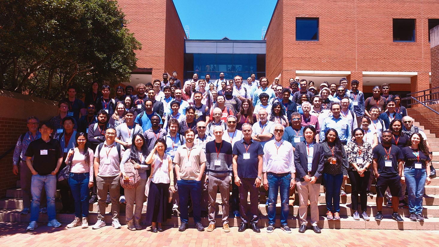 A large group of people standing on steps outside academic buildings